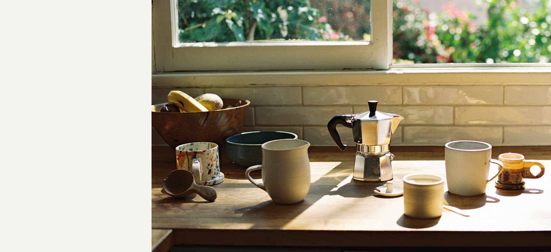 Ceramic mugs and a mokapot for coffee on a wooden counter
