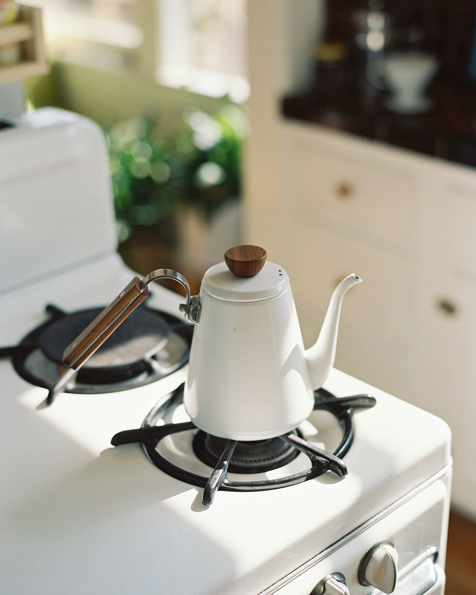 A white enamel kettle by Bona with a wooden handle